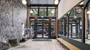 Un interior moderno con un banco de madera, una silla colgante y un acceso por puerta de vidrio.