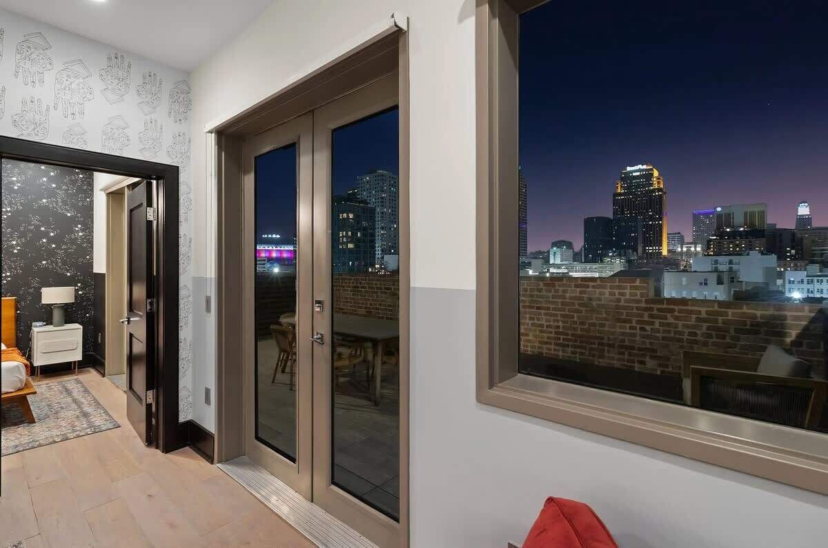 A modern room with a city view, a sliding glass door, and a dining area visible through the door.