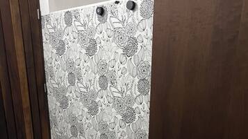 A room with a patterned wallpaper, a wooden door, and a plain wall.