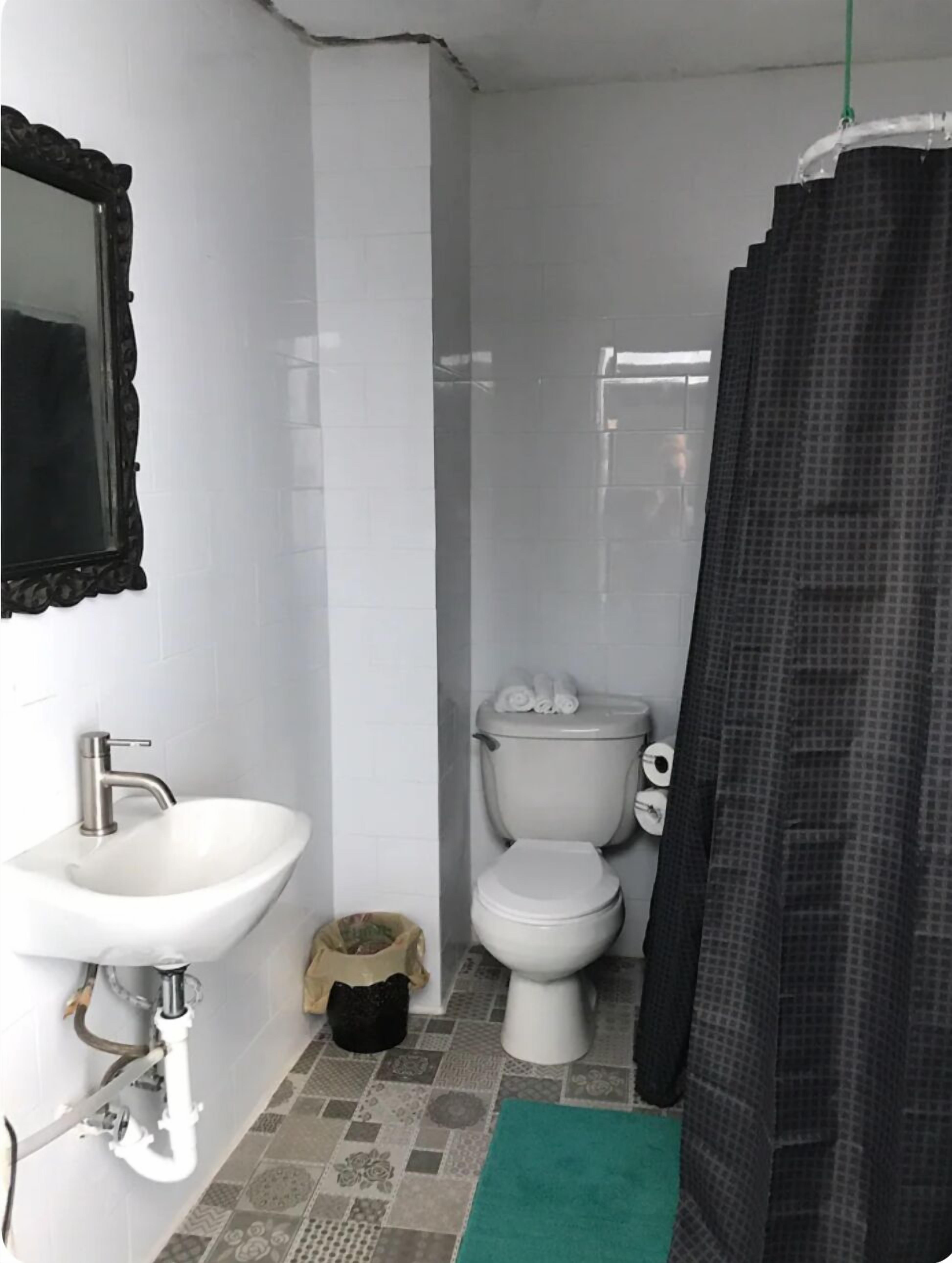 Un baño pequeño con un lavamanos blanco, un inodoro y una cortina de ducha.