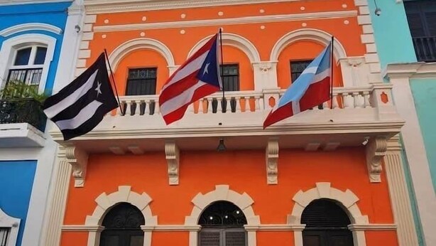Een gebouw met drie vlaggen, waarvan er twee Puerto Ricaans zijn en één Dominicaans.