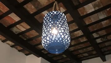 A room with a rustic ceiling, a blue hanging light fixture, a door, and a zebra painting on the wall.