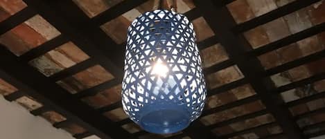 A room with a rustic ceiling, a blue hanging light fixture, a door, and a zebra painting on the wall.