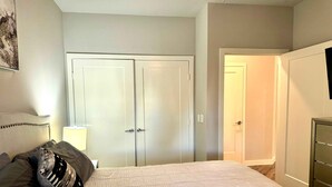A bedroom with a bed, a wardrobe, and a door leading to another room.