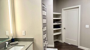 A bathroom with a sink, mirror, towel, and storage shelves.