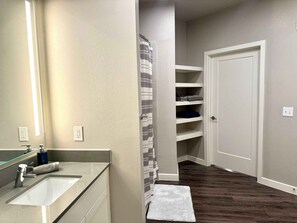 A bathroom with a sink, mirror, towel, and storage shelves. - MCK104 - Apt|Patio|15mi to Toyota Stadium|Sleeps 2 (McKinney)