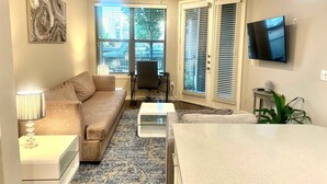 A living room with a sofa, coffee table, TV, and a ceiling fan.