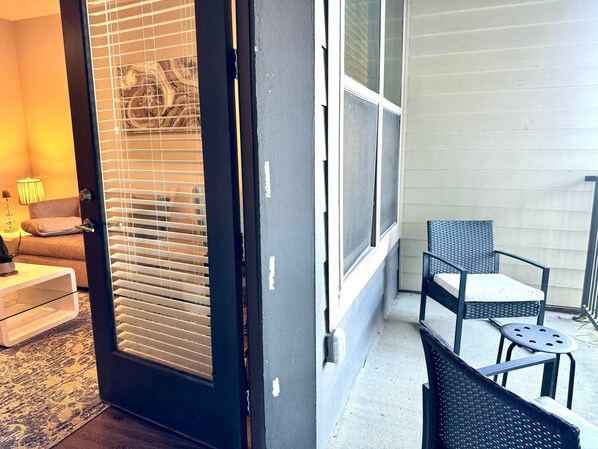 A room with a sliding door, a chair, a small table, and a lamp.