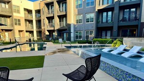 A modern outdoor pool area with lounge chairs and a clear view of the surrounding buildings.