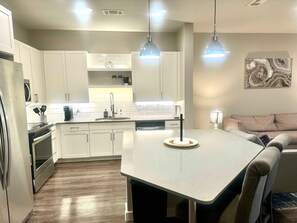 A modern kitchen with white cabinetry, a central island, and pendant lighting.
