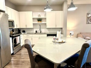 A modern kitchen with white cabinets, a central island, and pendant lighting.