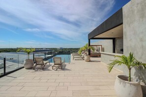 A rooftop terrace with a pool, lounge chairs, and potted plants. - Perfect Location, Balcony, Rooftop Pool, Gym (Tulum)