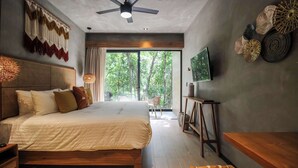 A modern bedroom with a large bed, ceiling fan, and a view of the outdoors.