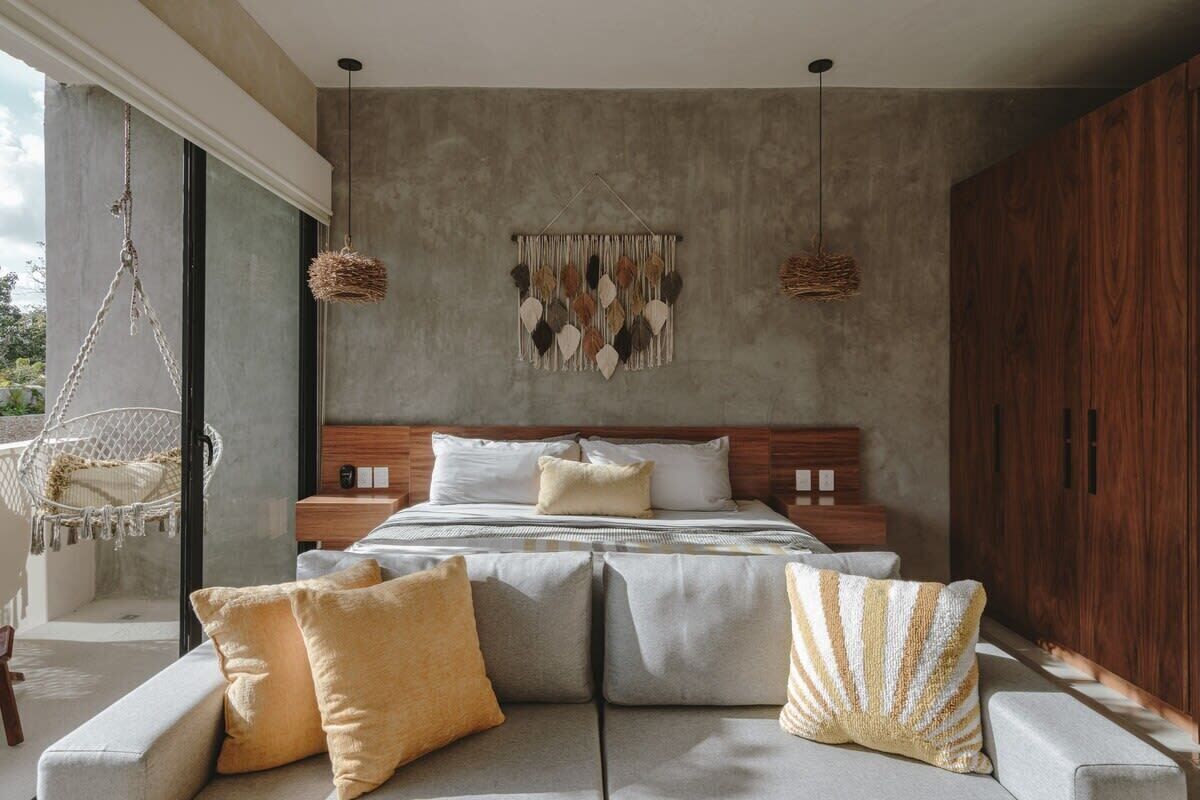 Un dormitorio moderno con una cama grande, un sillón colgante y una obra de arte en la pared.