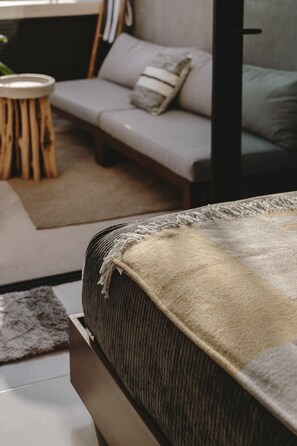 A modern living room with a sofa, a round wooden side table, and a large rug. - Casa Felipa | Chic Jungle Hideaway w/ Private Pool (Tulum)