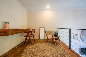 A room with a wooden floor, a round woven rug, wooden chairs, a small table, a potted plant, and a wall-mounted shelf. - Bright & Sunny 2BR Loft w/ Roof Pool in Downtown (Tulum)