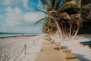 A beach with lounge chairs and palm trees. - Terrace Condo w/ Pool & Concierge Service (Tulum)