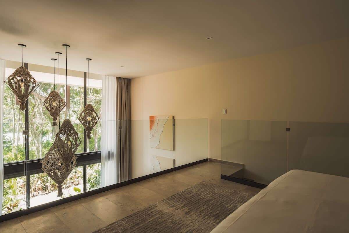 A modern hotel room with a large window, a bed, and a decorative wall piece.