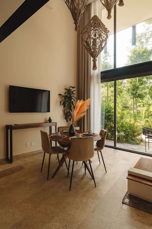 Uma sala de jantar moderna com uma janela grande, uma televisão de tela plana e um lustre decorativo.