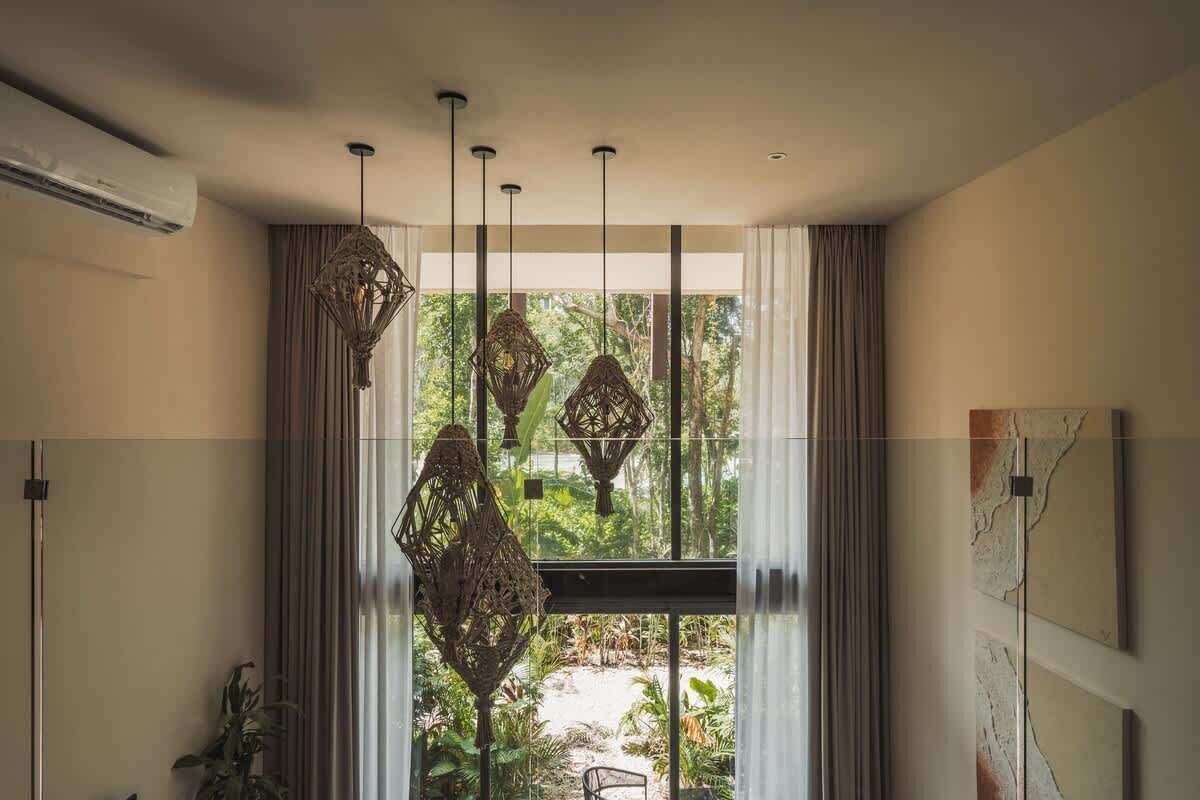 A modern bathroom with a large window, a hanging light fixture, and a wall-mounted air conditioner.