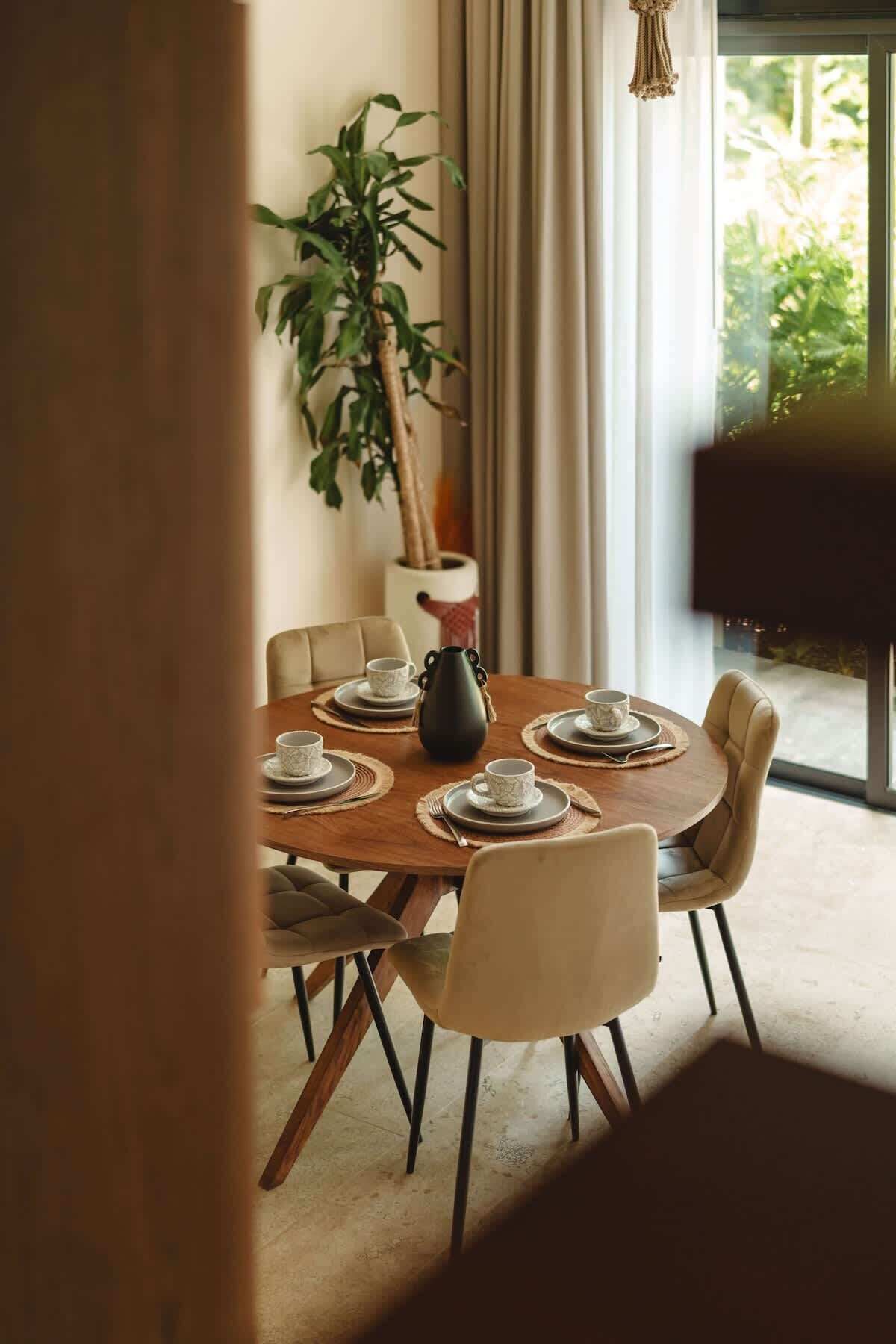 A dining area with a round table set for six, surrounded by chairs.
