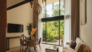 Una sala moderna con un televisor grande, comedor y un sofá con vistas a zonas verdes.
