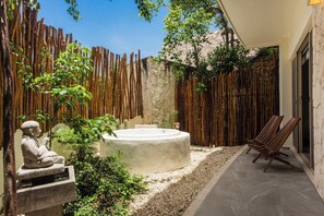 Een wellnessruimte met een jacuzzi, houten omheining en een standbeeld.