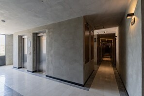 A modern hallway with elevators and a long corridor leading to a darkened area. - Tulum Studio: Rooftop Pool & Padel Court Access (Tulum)
