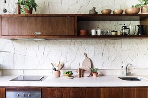 A kitchen with a marble backsplash, wooden cabinets, a stainless steel sink, and various kitchen utensils and plants.