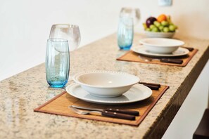 A kitchen counter with a bowl, a glass, and a fruit bowl.