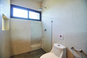 A small bathroom with a toilet, a shower, and a window.