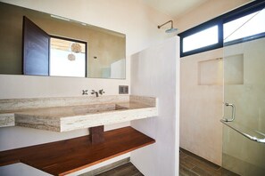 A modern bathroom with a large mirror, a marble sink, and a glass shower enclosure.
