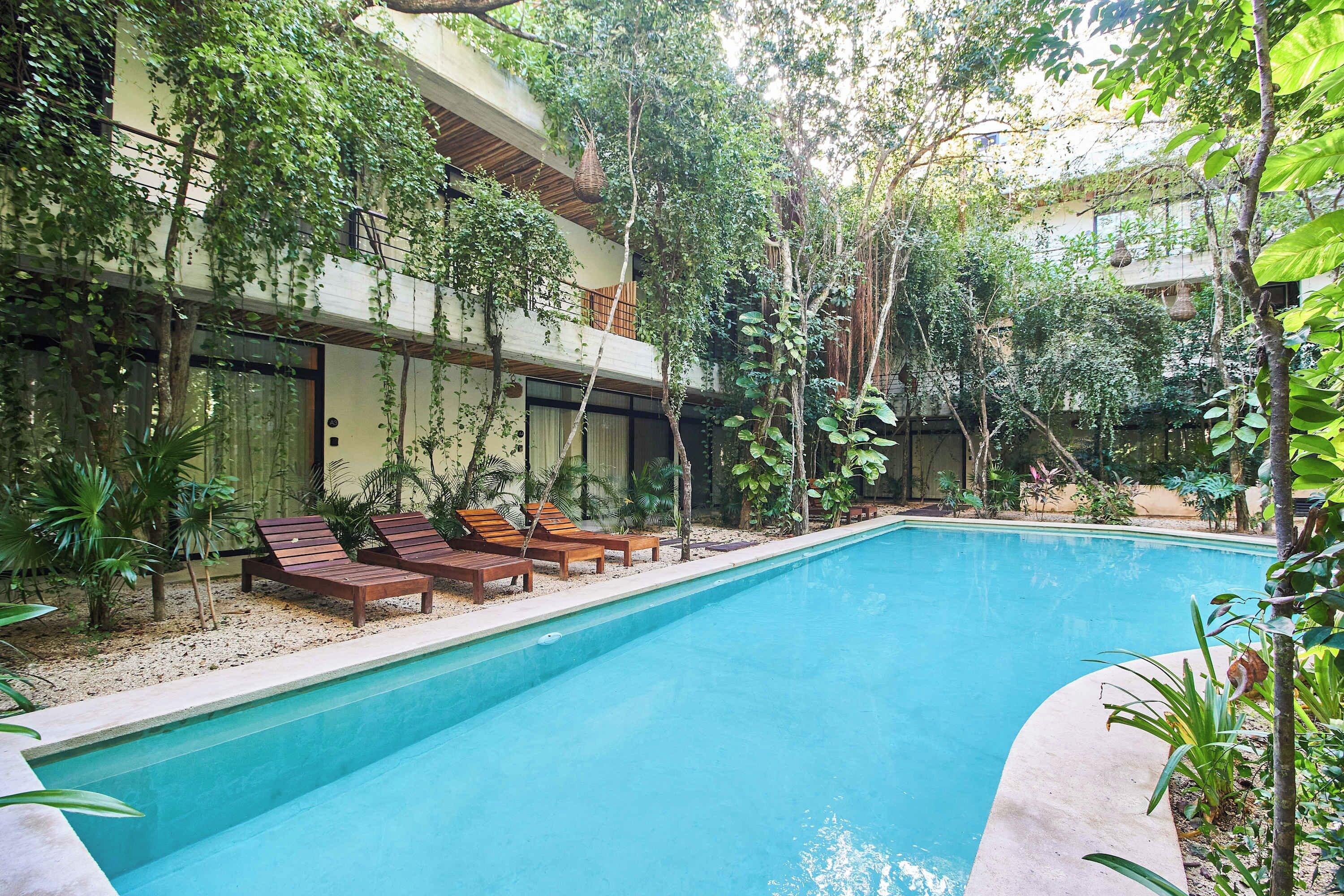 A swimming pool with lounge chairs and a garden area with trees and plants.