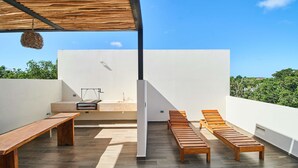 A rooftop terrace with a wooden bench, a lounge chair, and a small sink. - Tulum Penthouse with Rooftop Pool and BBQ Grill (Tulum)