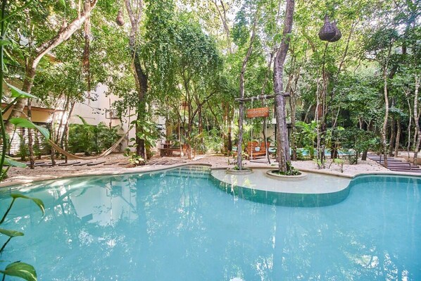 A swimming pool surrounded by trees and a hammock.