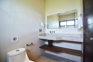 A bathroom with a toilet, a sink with a mirror, and a towel rack. - Tulum Penthouse w/ Private Roof Pool & BBQ Grill (Tulum)