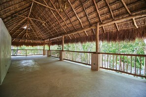 An open-roofed structure with a wooden ceiling and a balcony railing.