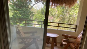 Un balcon doté de mobilier en bois, comprenant une table et des chaises, et offrant une vue sur la verdure environnante.
