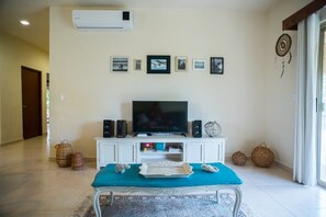 A living room with a TV, speakers, and framed pictures on the wall.