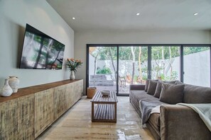 A modern living room with a wooden cabinet, a sofa, a coffee table, and a large window.