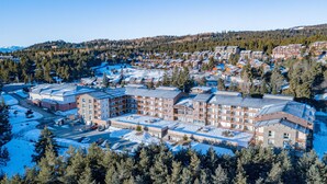 A large hotel with multiple floors and a central courtyard, surrounded by snow-covered ground and dense forest.