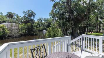 A deck with a table and chairs overlooking a river and trees.