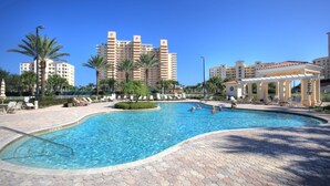 A swimming pool with a hexagonal tiled deck, surrounded by palm trees and lounge chairs.