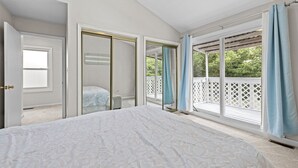 A bedroom with a large bed, a walk-in closet, and a sliding glass door leading to a balcony. - Cozy 3-bedroom condo with AC and WiFi in charming Virginia Beach (Virginia Beach)