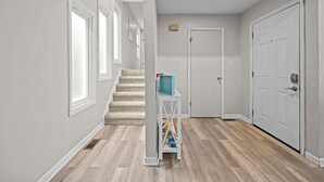 A hallway with a staircase, a door, and a sign that reads "beach". - Cozy 3-bedroom condo with AC and WiFi in charming Virginia Beach (Virginia Beach)