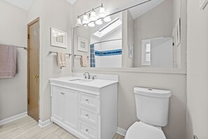 Une salle de bain moderne avec un meuble-lavabo blanc, un grand miroir et des toilettes.