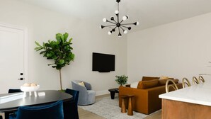 Ein modernes Wohnzimmer mit Essbereich, einer großen Pflanze und einem Flachbildfernseher an der Wand.