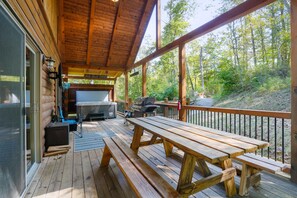 A wooden deck with a grill and seating area, surrounded by trees. - Freedom Ridge Cabin | Hocking Hills, Hot Tub (Logan)