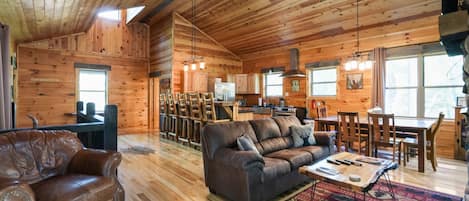 Un intérieur spacieux de chalet en bois, avec un coin repas en bois, un canapé et une cuisine.