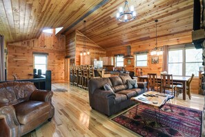 Un interior espacioso de cabaña de madera con una zona de comedor de madera, un sofá y una cocina.